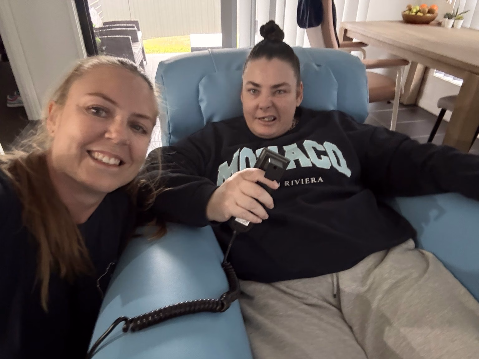 Charmaine with Sally on delivery day, seated in her new blue chair