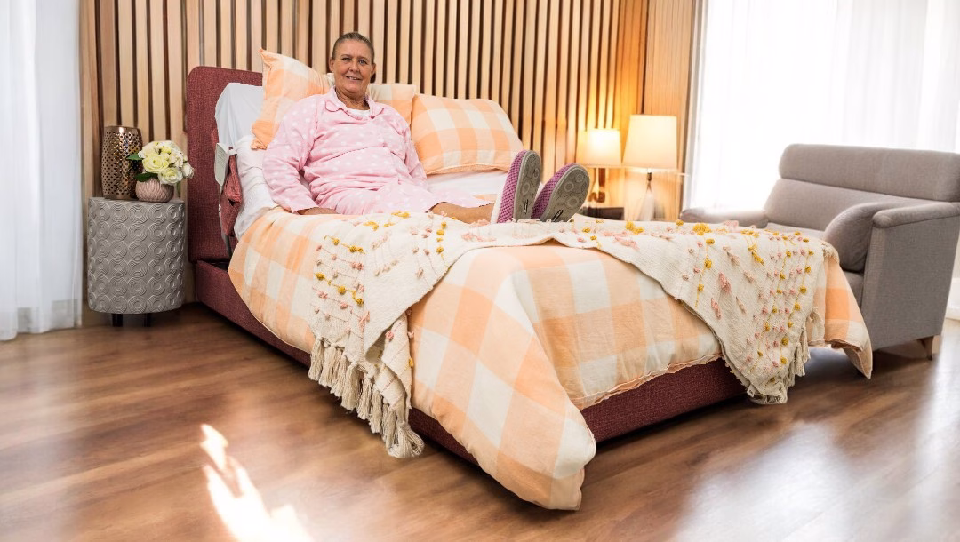 Person sitting in a Novacustom HiLo bed in a home bedroom